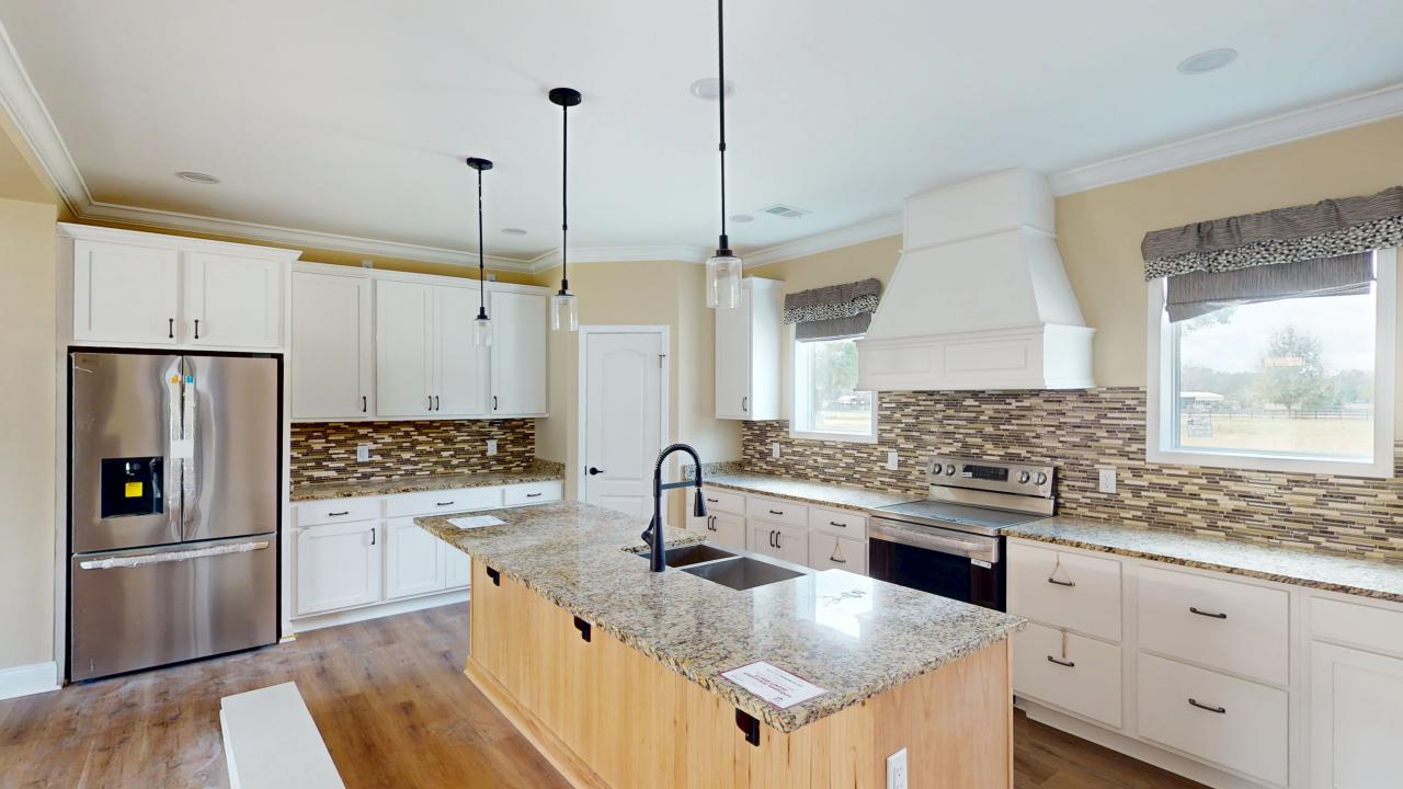 Kitchen with granite island and white cabinets inside The Brantley model home at Florida Prefab Modular Homes